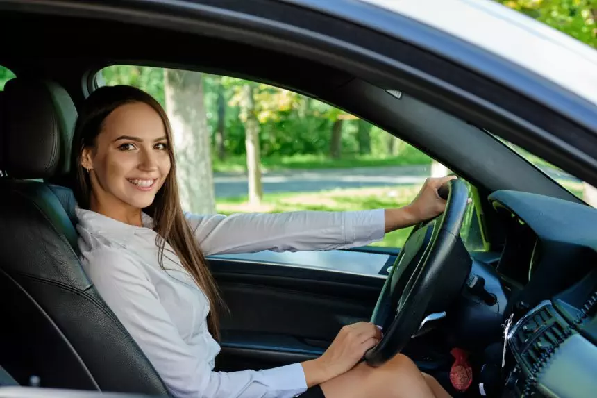 Beautiful smiling brunette girl behind the wheel of a car