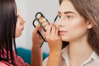 Makeup artist applies eye shadow. Beautiful woman face. Perfect makeup
