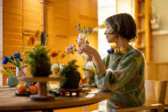 Woman sits by the table full of flowers at home