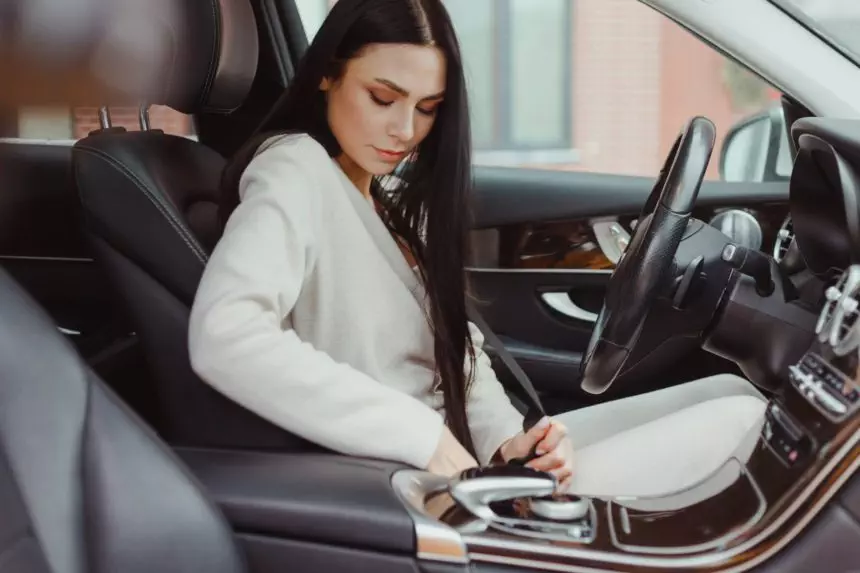 Young caucasian woman driver fasten seat belt in car, preparing for driving